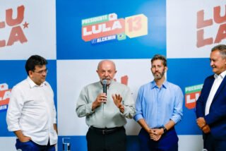 Lula fala ao microfone, acompanhado de aliados, em Brasília, em 6 de outubro de 2026